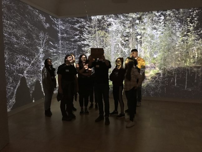 <p>Exhibiting artist Abe Avnisan shows members of the Henry Teen Art Collective his installation, <em>Sin Sol, Forest Memory</em>, a collaboration with artist micha cárdenas<em>.</em> Photo: Katrina Herzog.<br /></p>
